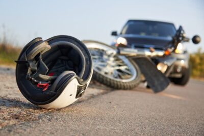 motorcycle and helmet crashed on road in front of car