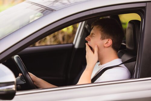 young driver yawning behind the wheel