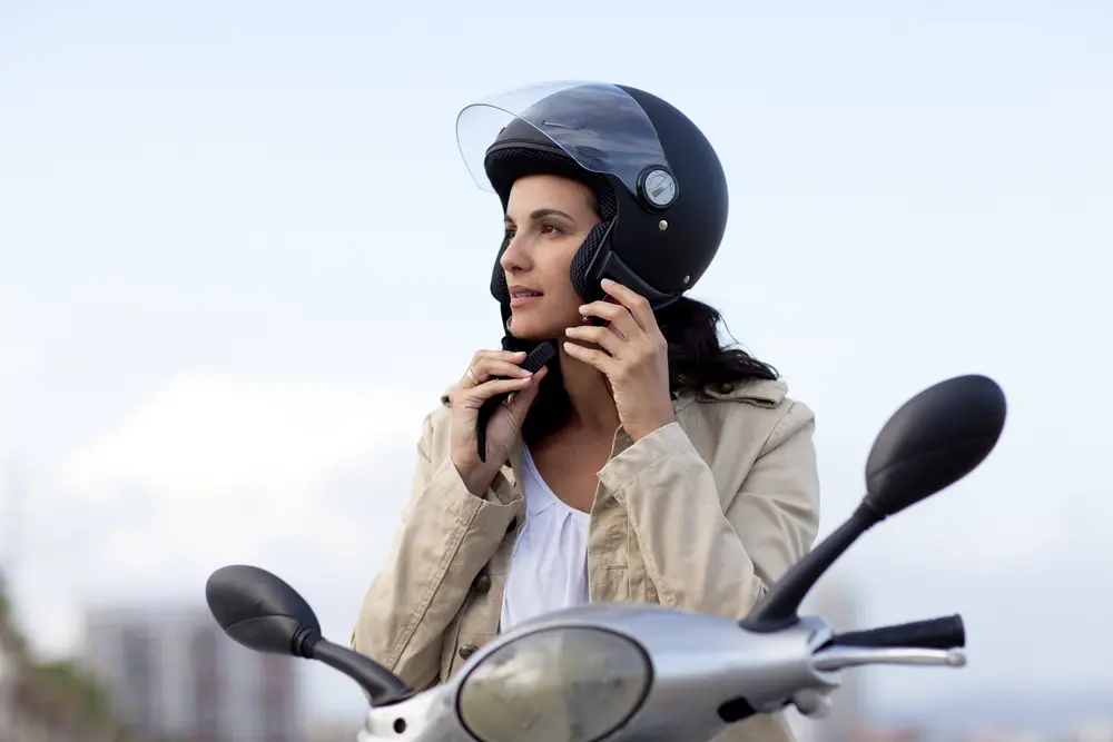 woman happily fastening a motorcycle helmet