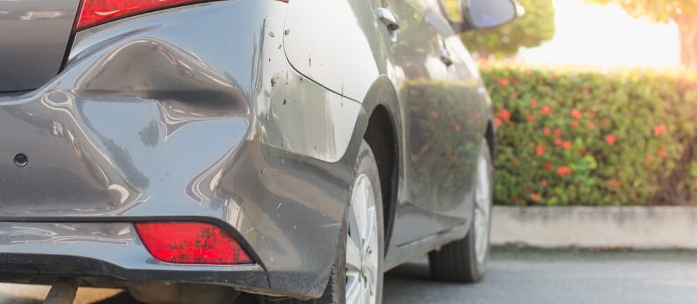 grey car with dent in the back bumper, in a Wilmington parking lot, that was involved in a hit and run