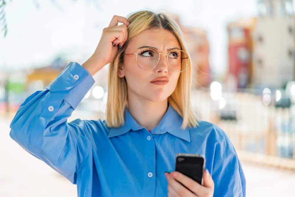 confused blonde woman using mobile phone