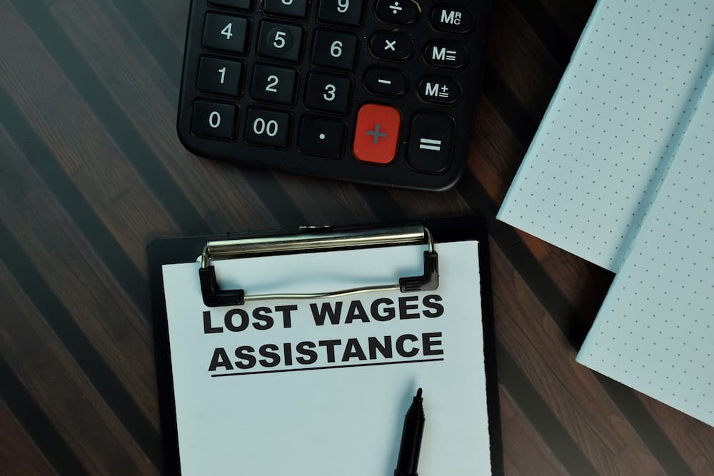 A clipboard labeled "Lost Wages Assistance" next to a calculator and notebook, representing financial help for lost wages due to injury or illness.