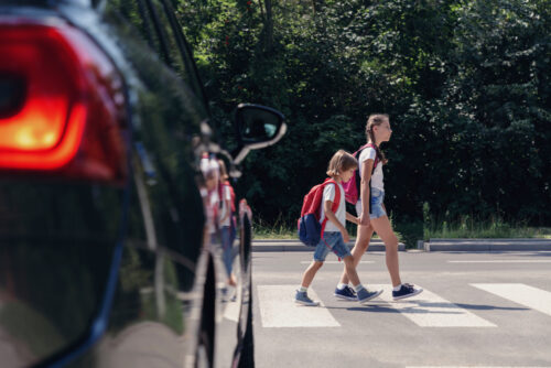 little boy and girl holding hands walking through a pedestrian sign